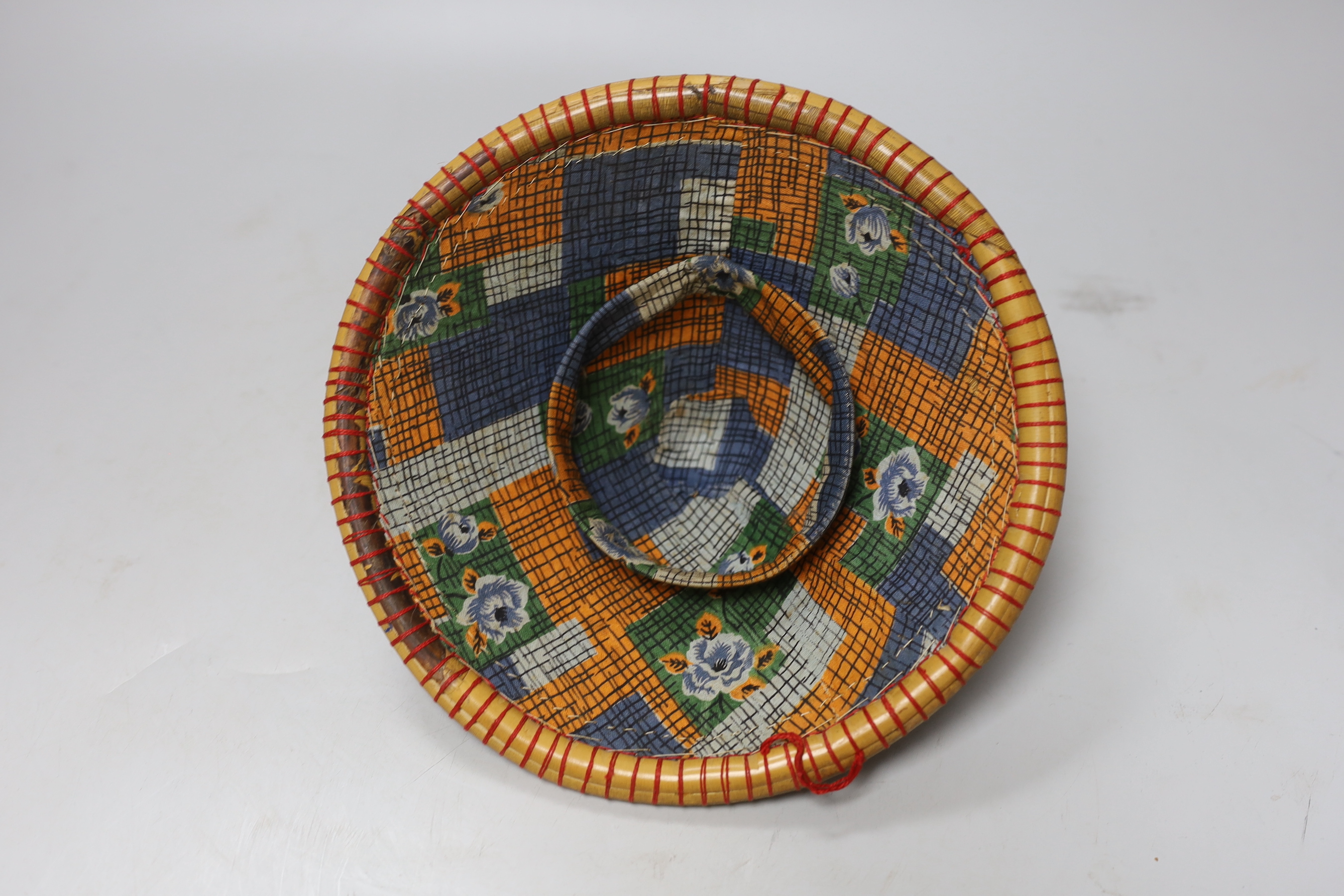 Three red and black striped bamboo rice hats, together with a smaller rice hat with beaded flag decoration